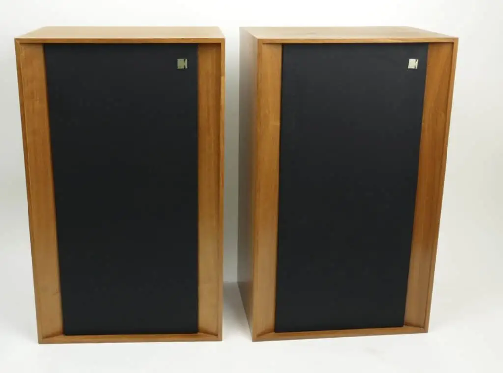 Een paar vintage KEF Concerto-luidsprekers met houten kasten en zwarte stoffen frontjes, staand tegen een witte achtergrond
