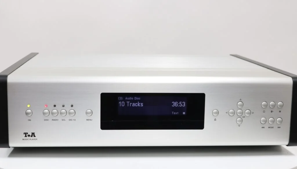 Een zilver/zwart T+A Music Player met minimalistische ontwerp en diverse bedieningsknoppen aan de voorkant.