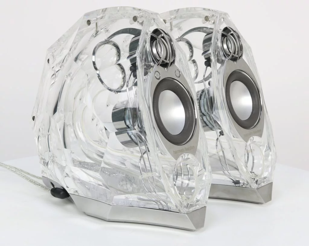Transparante Harman Kardon GLA-55 luidsprekers met gereviseerde woofer en modern kristalontwerp, op een stijlvolle ondergrond.