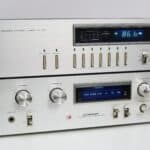 Vooraanzicht van de Pioneer SA-510 versterker met zilveren frontpaneel en blauwe displayverlichting.